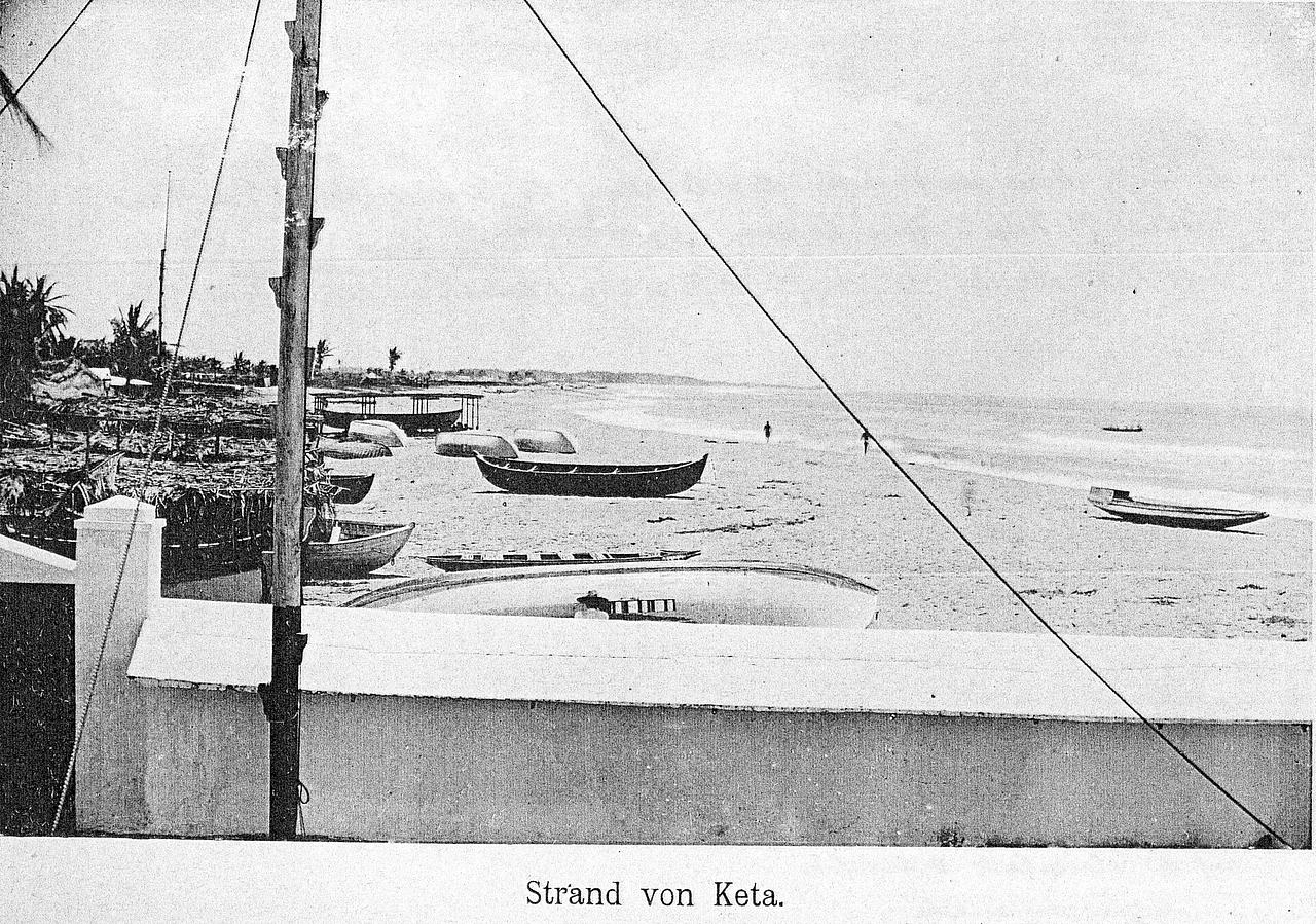Fishing Boats on the beach of Keta. The white wall in the foreground belongs to the factory of the company Friedrich M. Vietor and Sons, Bremen.