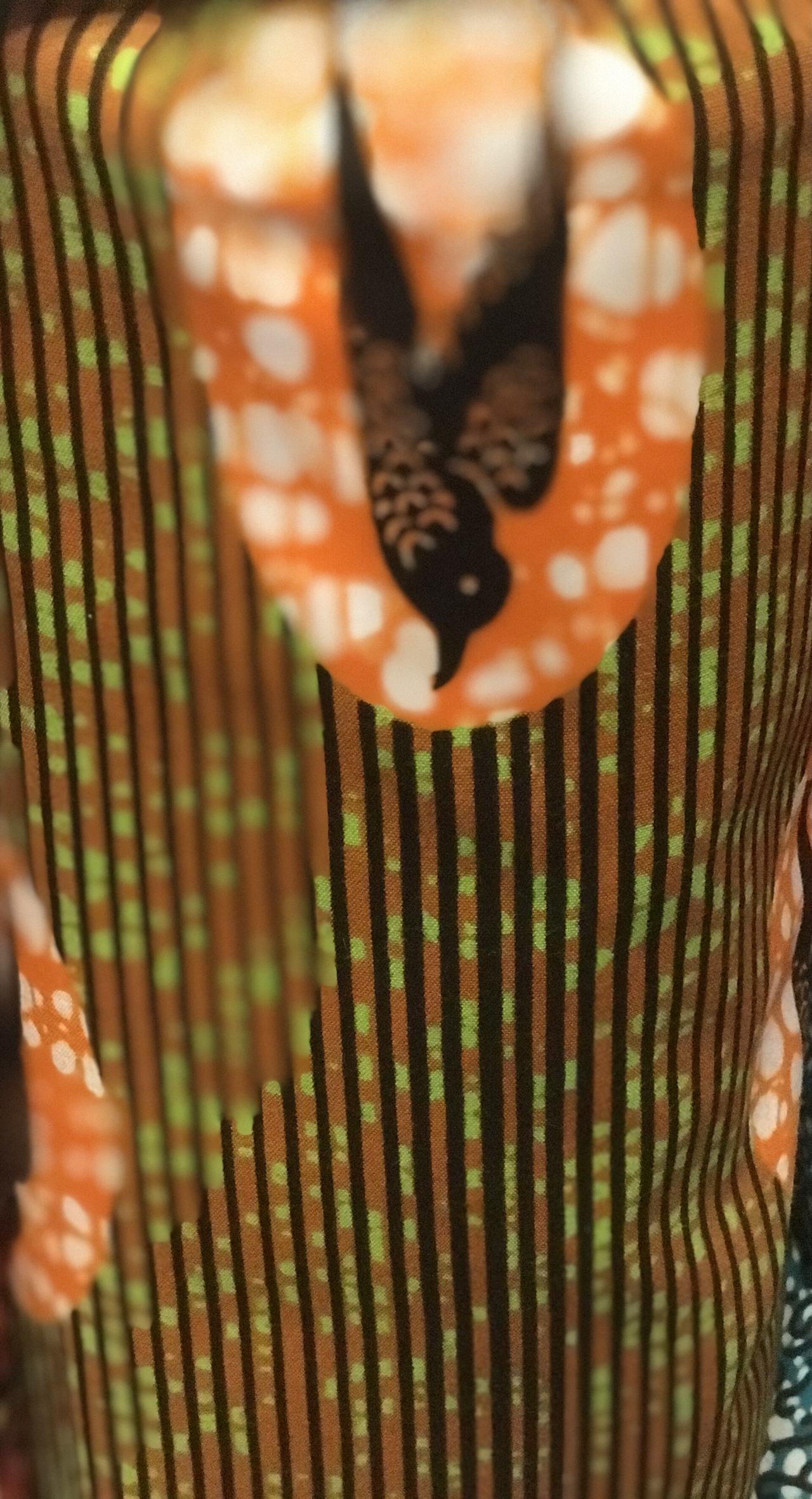 This fabric's design components includes a colored motif with lines and a flying bird on a colored background in an oval shape
