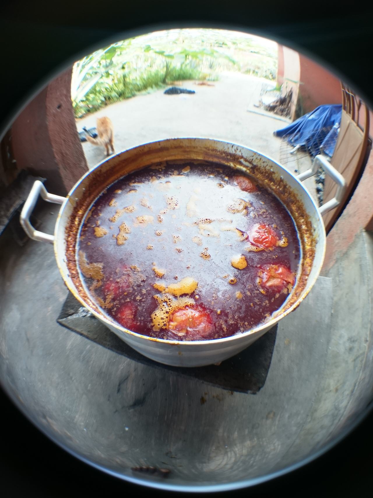 A fisheye view of palm nut soup on a coal pot