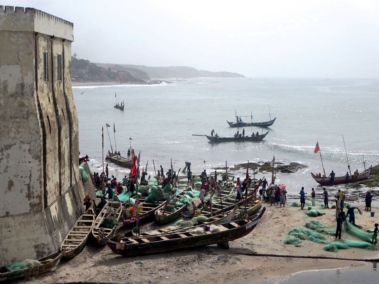 Gulf of Guinea fishing boats congregate below the battlements of Cape Coast Castle (1637), Ghana.