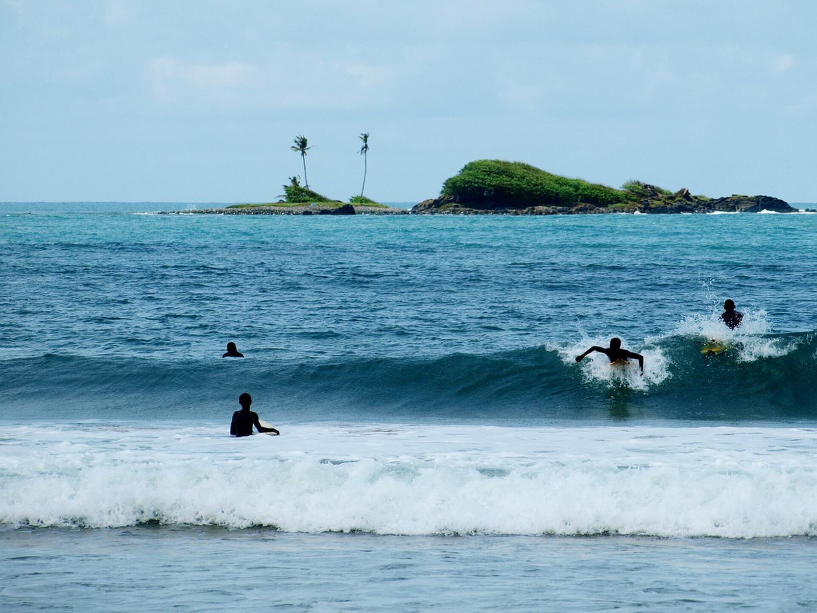 Surfers riding waves at Busua Beach, Ghana's surf destination.