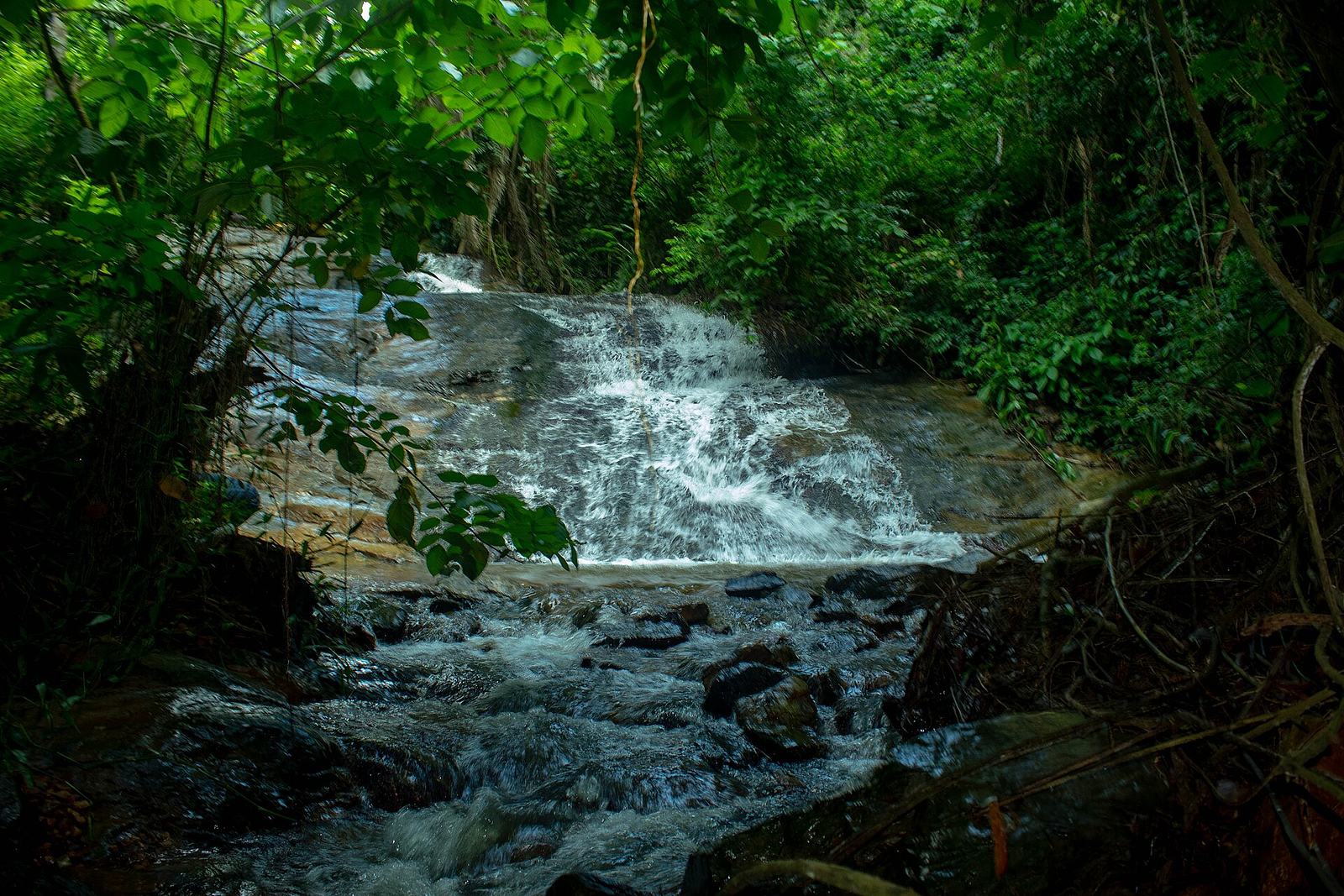 Water cascading over layered rocks at Obosomase Waterfalls in Ghana's Eastern Region