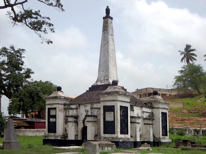 Weathered stone monument and graves at the Old Dutch Cemetery in Elmina, Ghana.