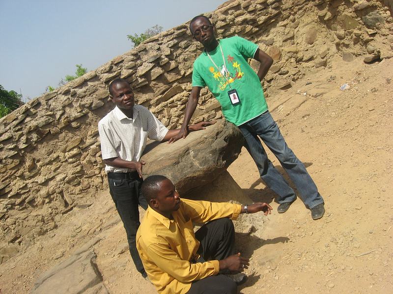 A large dark rock formation standing beside a road at the edge of Larabanga village, Ghana.