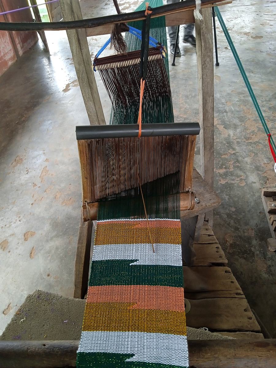 A weaver working at a traditional narrow-strip kente loom in Tafi, Volta region, Ghana.
