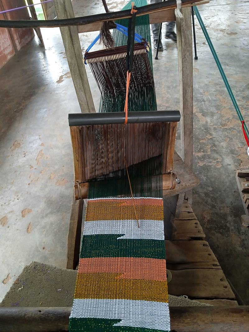 A weaver working at a traditional narrow-strip kente loom in Tafi, Volta region, Ghana.