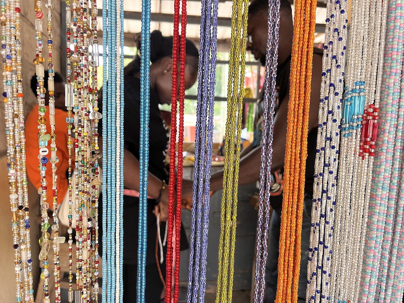 Vendor fitting waist beads for a customer at a stall in the Koforidua Beads Market