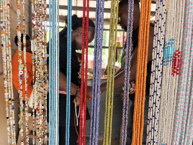Vendor fitting waist beads for a customer at a stall in the Koforidua Beads Market