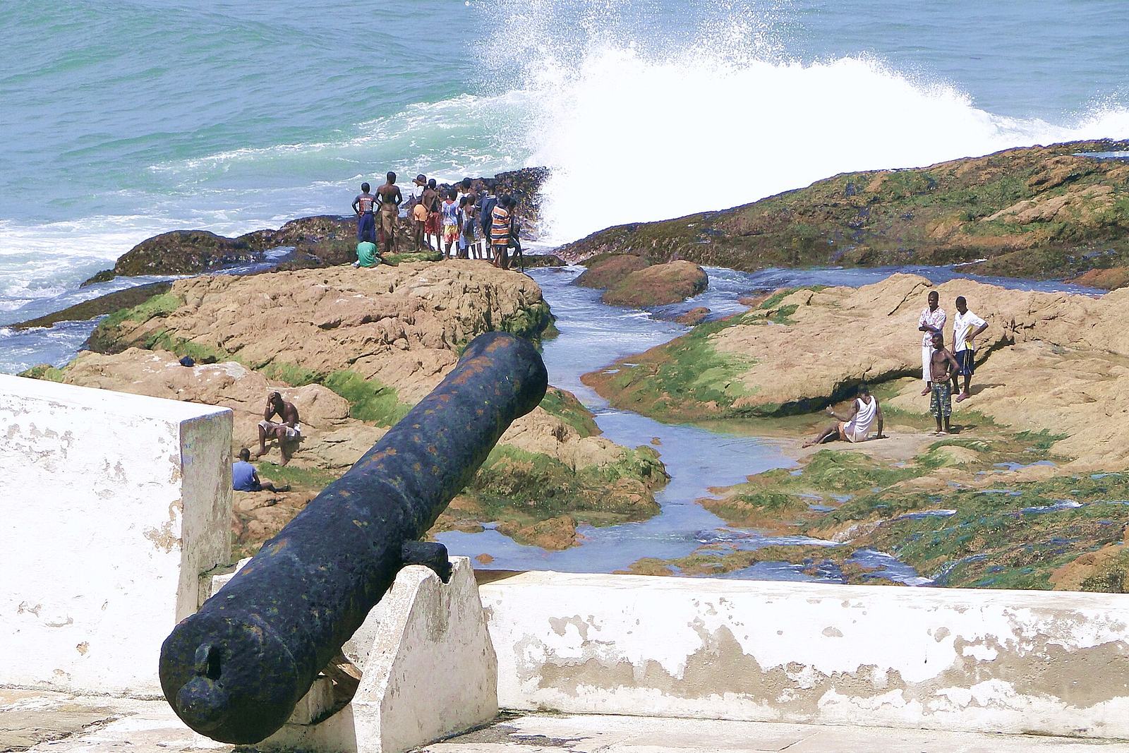 People on the seashore beneath the walls of Cape Coast Castle