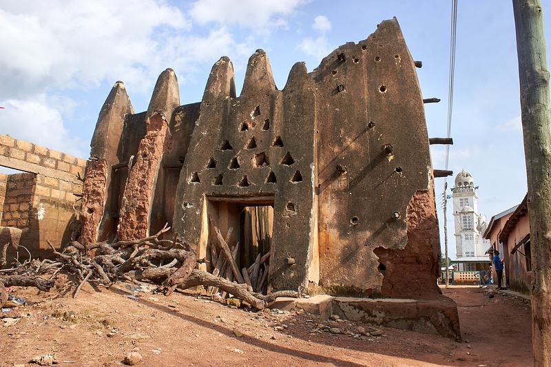Front elevation of the earthen Dondoli Old Central Mosque with buttresses and timber supports.
